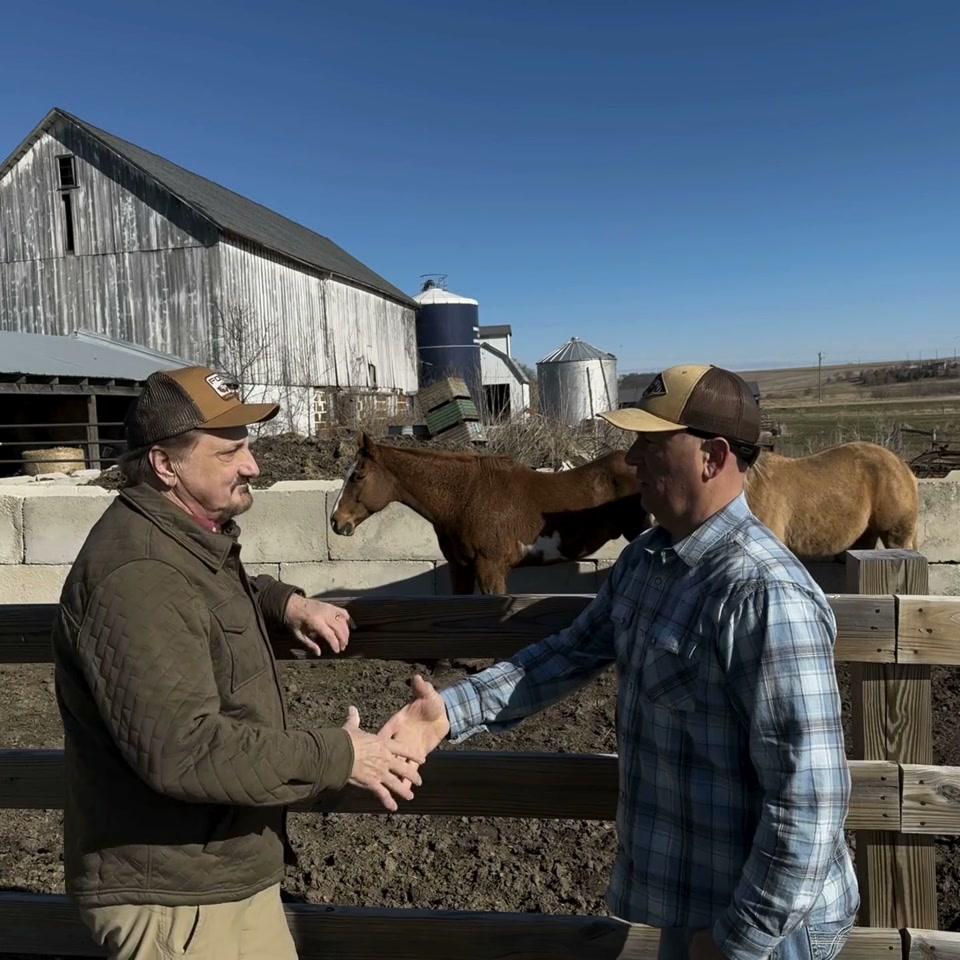 Jon Aleckson shaking hands with a farmer in front of a Wisconsin barn